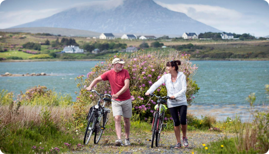 Two people riding bikes along a body of water
